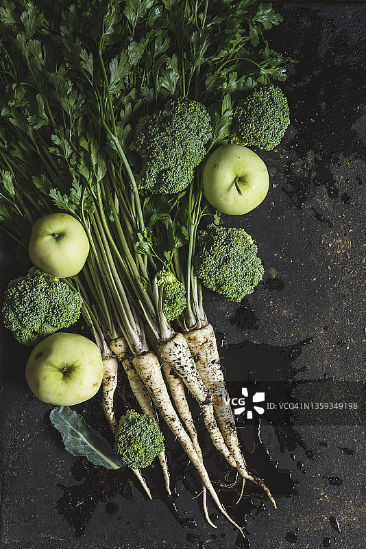 深色背景上的一束欧芹、西兰花和青苹果图片素材