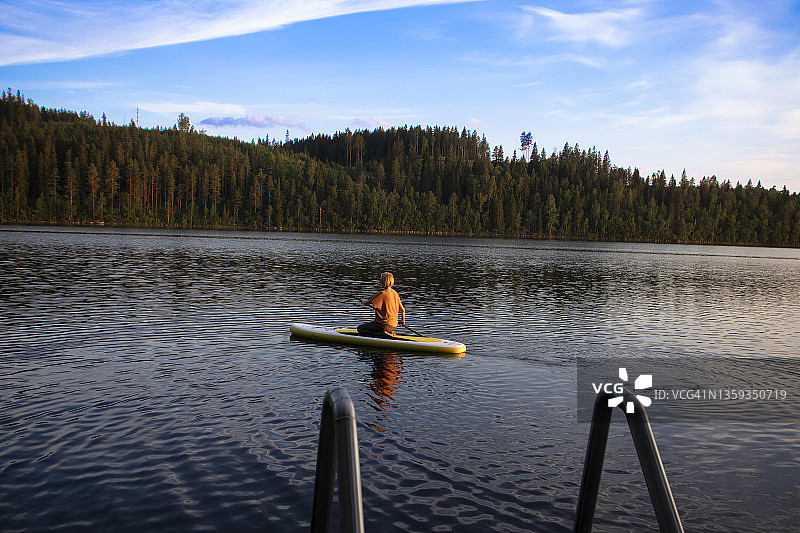 在色彩缤纷的夏日日落时，在皮划艇上放松的女人图片素材