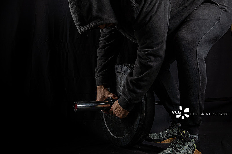 在黑色背景的影棚中举杠铃的男人图片素材