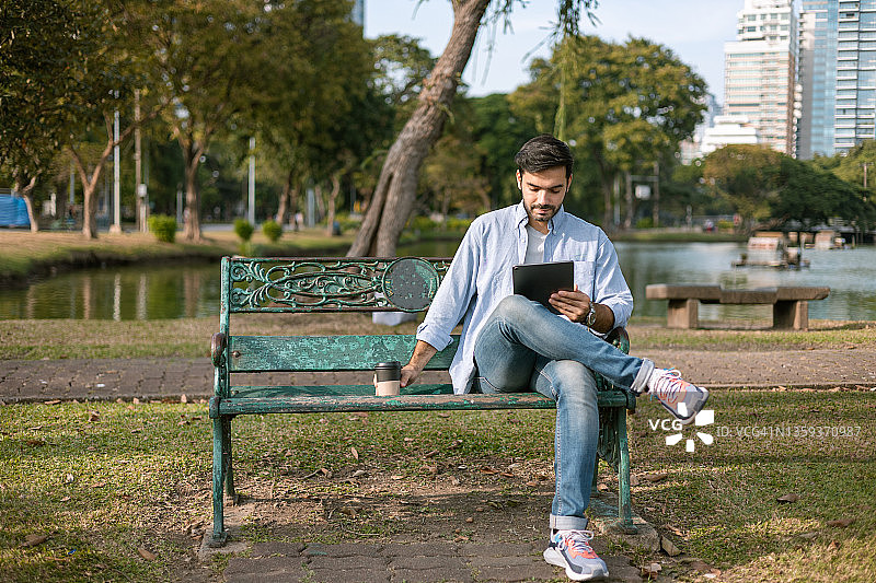 商人在泰国曼谷隆比尼公园长凳上使用平板电脑图片素材