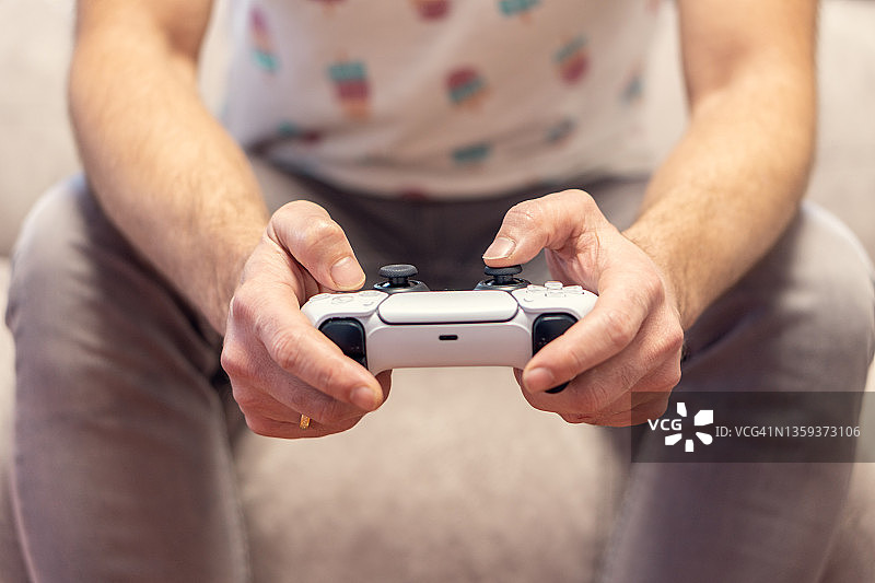在家里的沙发上玩电子游戏机的男人图片素材