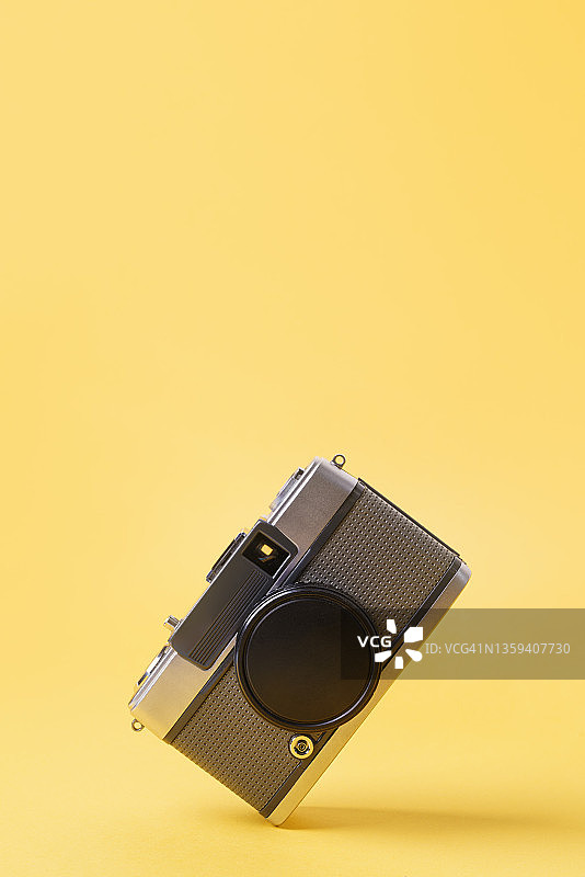 黄色背景上的复古35mm胶片相机图片素材