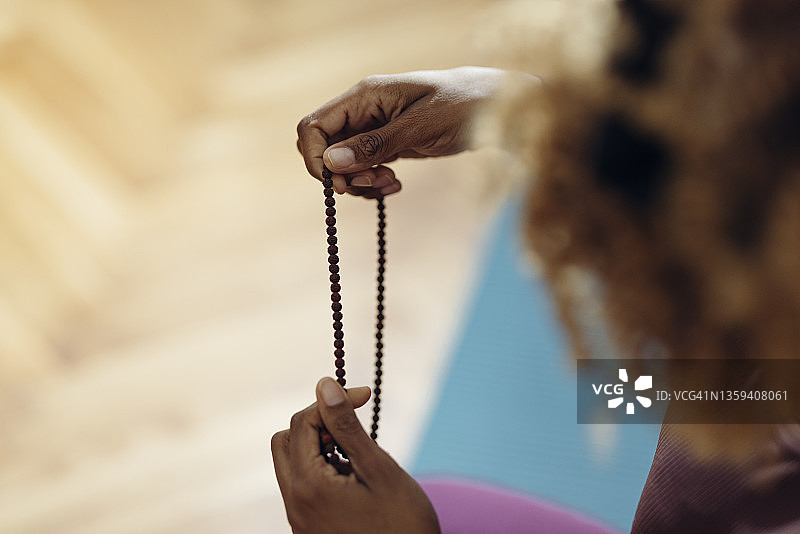 匿名女子在家使用念珠做瑜伽的特写镜头图片素材
