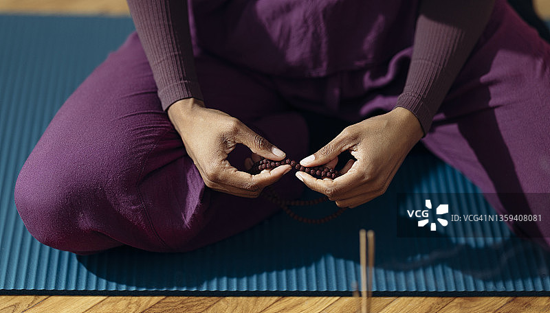 匿名女子在家使用念珠做瑜伽的特写镜头图片素材
