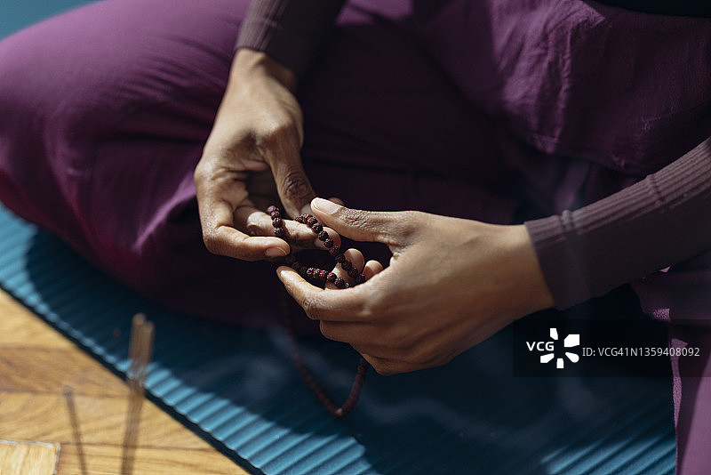 匿名女子在家使用念珠做瑜伽的特写镜头图片素材