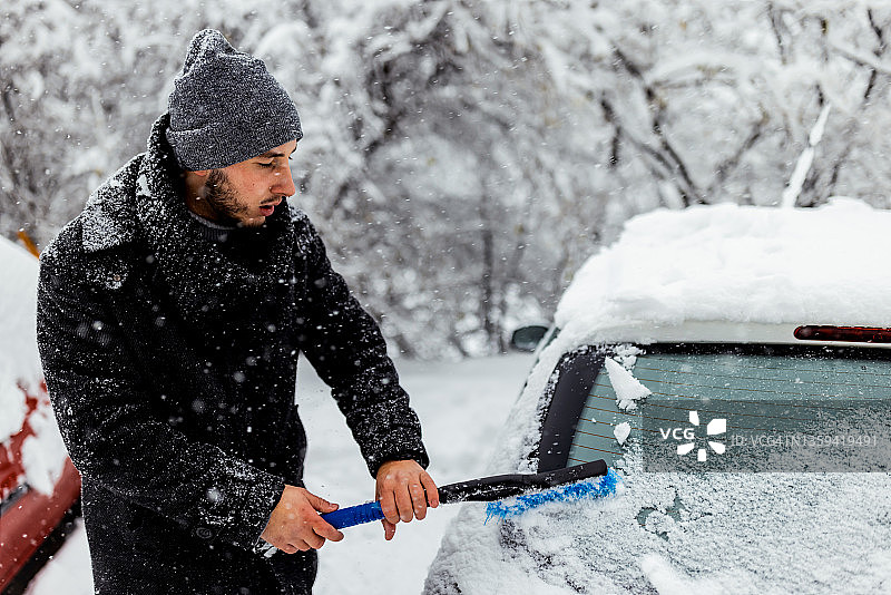 年轻男人清除汽车玻璃上的冰图片素材