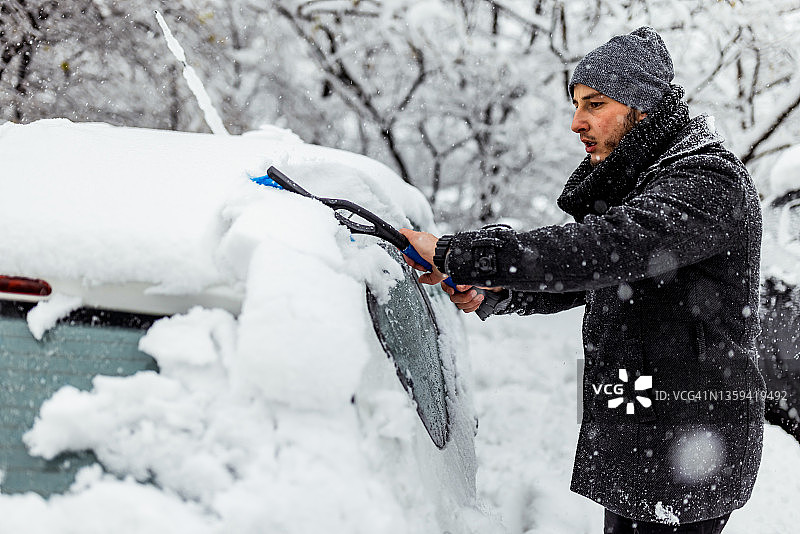年轻男人清除汽车玻璃上的冰图片素材