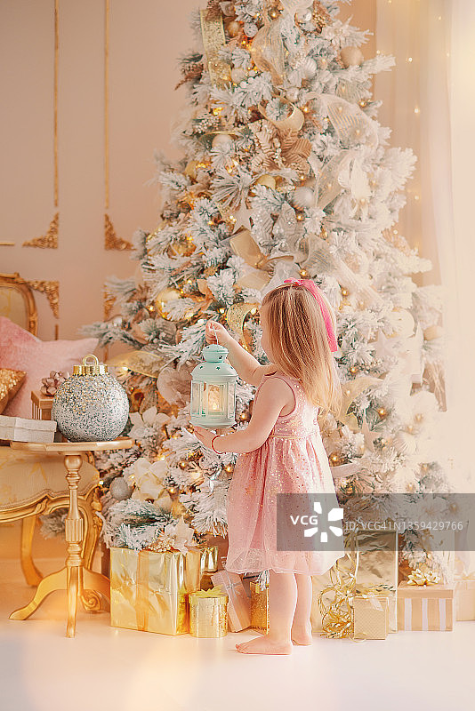 穿着粉色连衣裙装饰圣诞树的小女孩图片素材