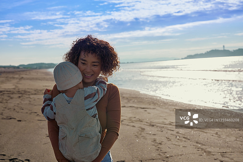 冲浪者母亲和孩子在海滩上行走图片素材