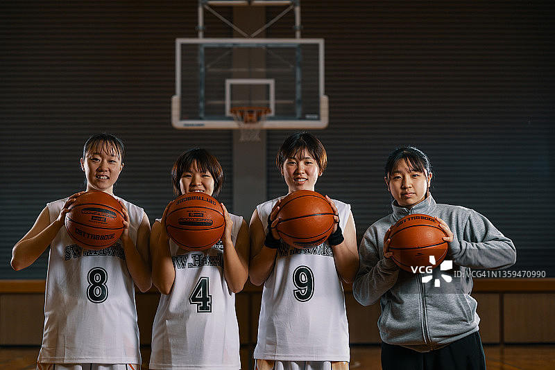 三位年轻的日本女篮运动员与她们的球队经理的合影图片素材