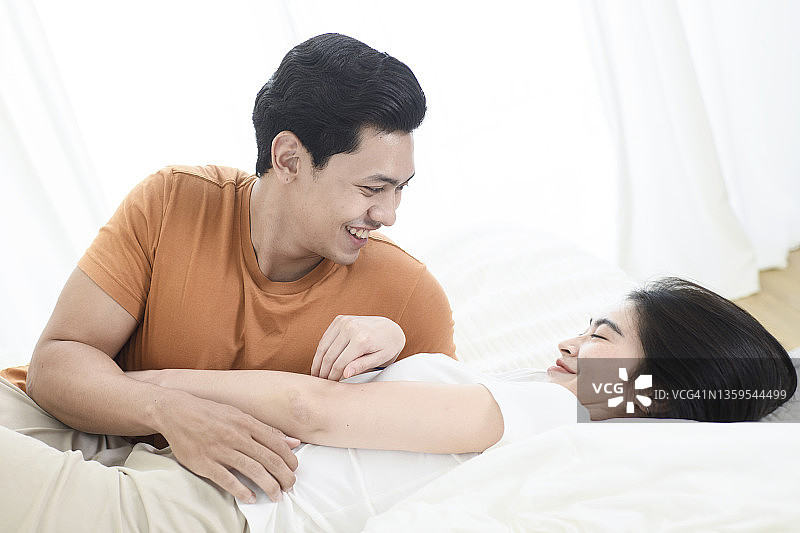 身着休闲装在床上放松的年轻情侣图片素材