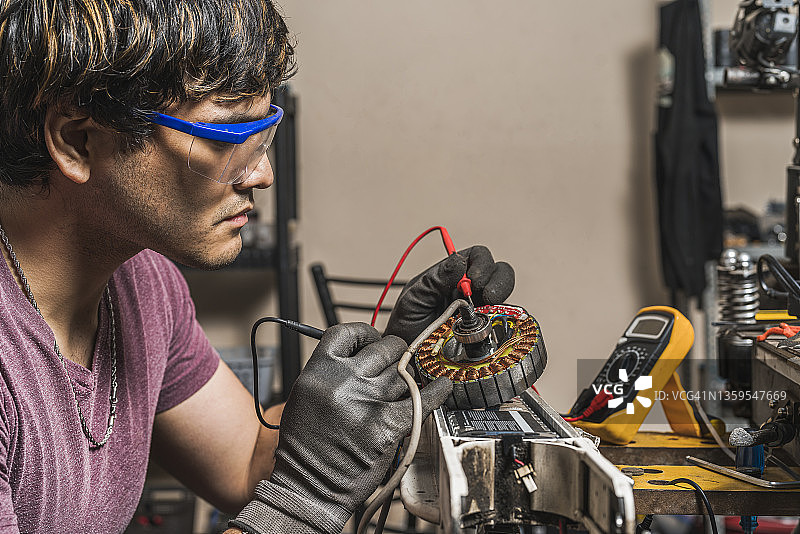 技工使用万用表检查踏板车的电压图片素材