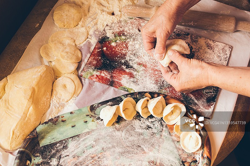 一位老妇人正在用面团制作肉馅饺子图片素材
