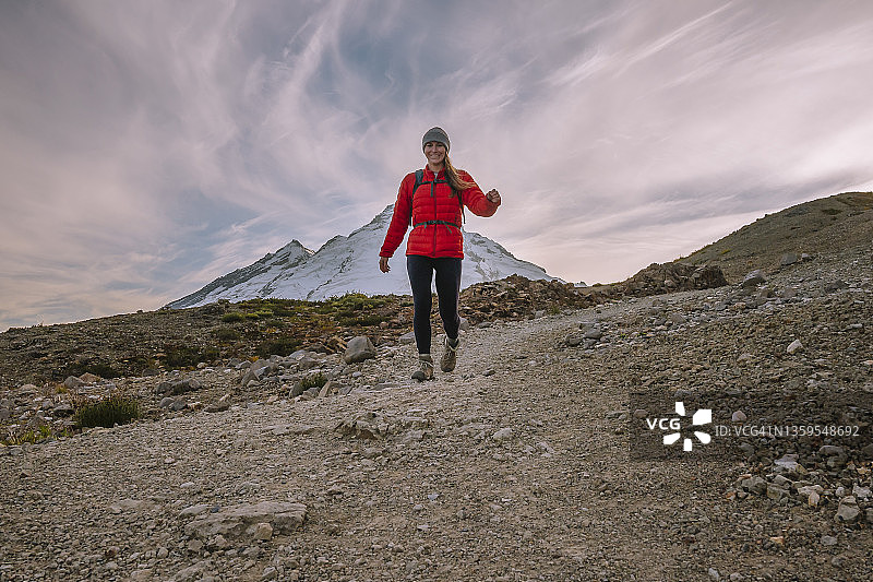 穿着紧身裤和红色羽绒服的女人在北喀斯喀特山脉徒步旅行图片素材