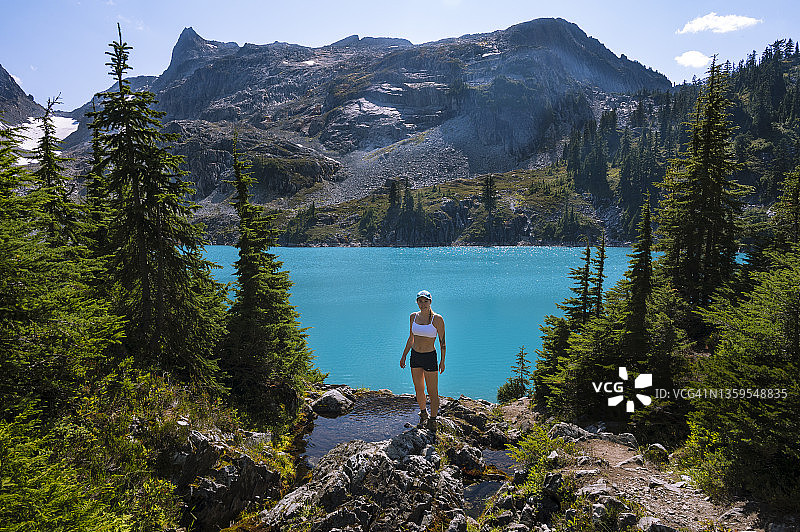 在美丽的蓝绿色湖前穿着露脐装的健康女性图片素材
