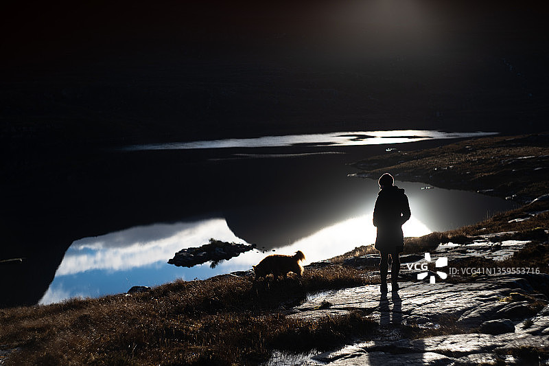 湖中倒映山景，女人和小狗的轮廓图片素材