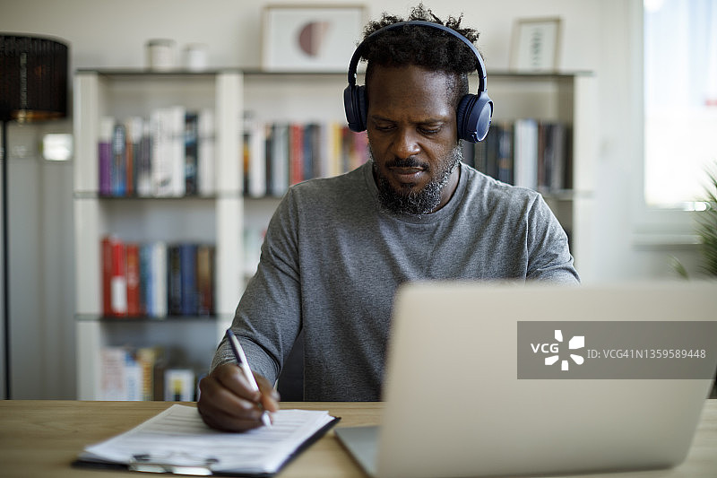 戴着蓝牙耳机在家办公的男人图片素材