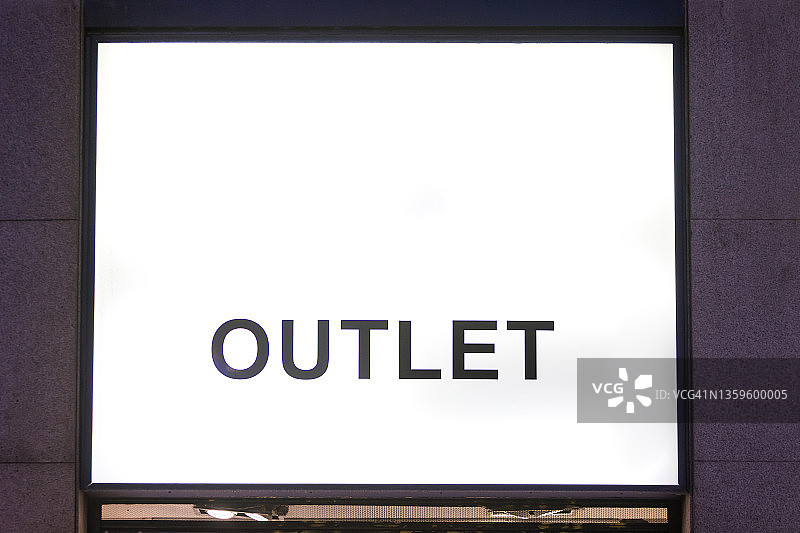 建筑物外墙上的发光白色灯牌，黑色字母写着“折扣店”，夜景，商店、夜生活、商业和折扣店概念图片素材