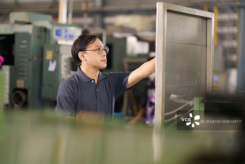 日本数控机床操作员在图表板上查看加工工作计划图片素材