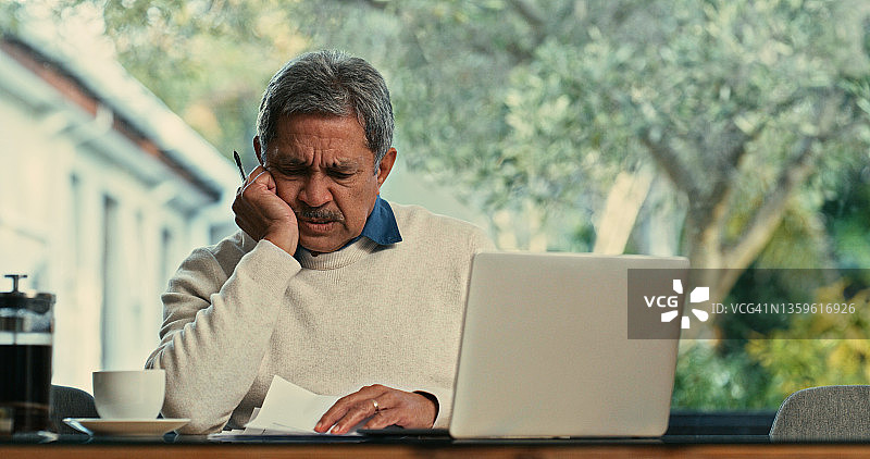 老年男人在家中使用笔记本电脑处理文书工作图片素材