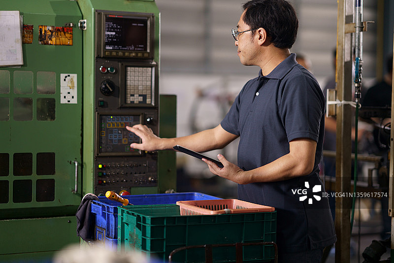 日本数控机床技师在控制面板上设置机器编程系统图片素材