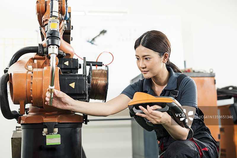 制造业中的机器人焊接检测，女焊接工程师根据汽车行业的质量控制标准检查工程零件的弧焊头图片素材