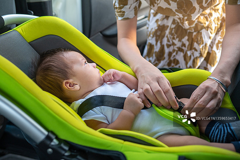 妈妈将新生男婴放入汽车安全座椅图片素材