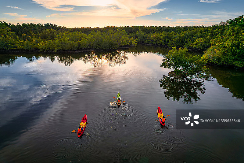 航拍：日落时分，人们在红树林环绕的运河中划皮划艇图片素材