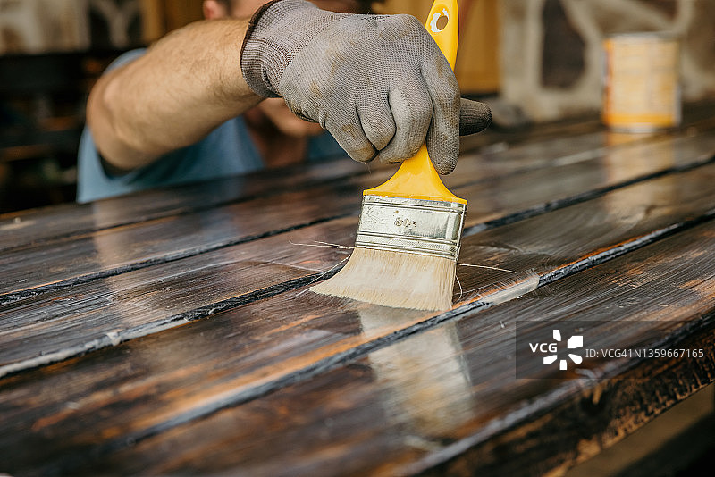 成年男人在油漆桌子，检查是否全部漆完图片素材