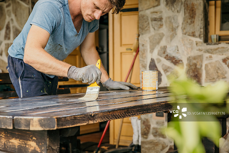 成年男人用黄色刷子粉刷木桌图片素材