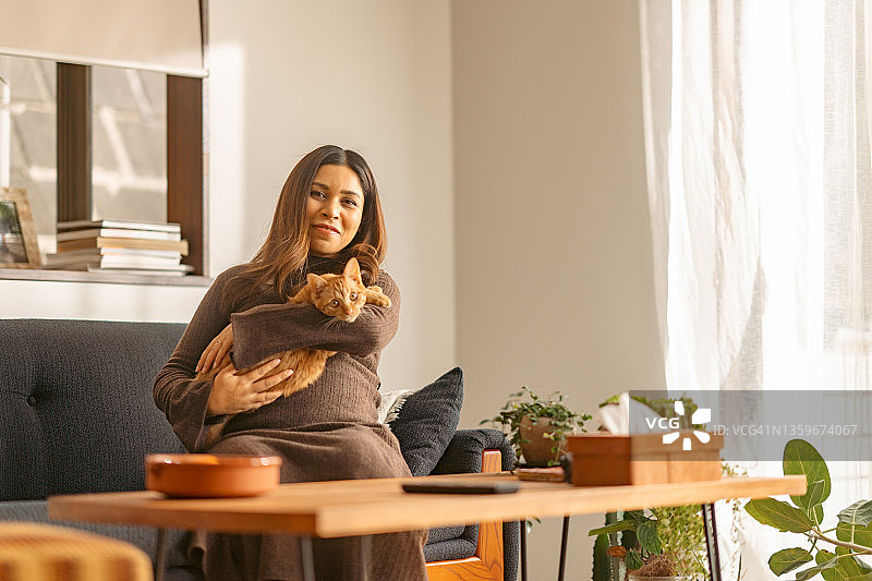 孕妇在家中客厅与姜黄色猫咪共度时光图片素材