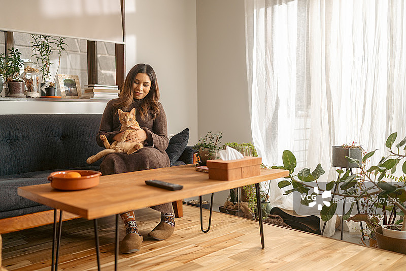 孕妇在家中客厅与姜黄色猫咪共度时光图片素材