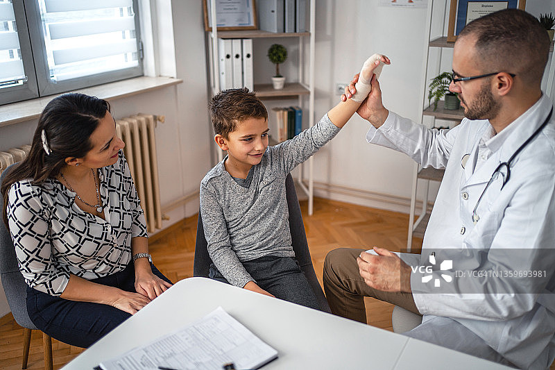 在儿科医生诊所接受手腕骨折治疗的小男孩图片素材