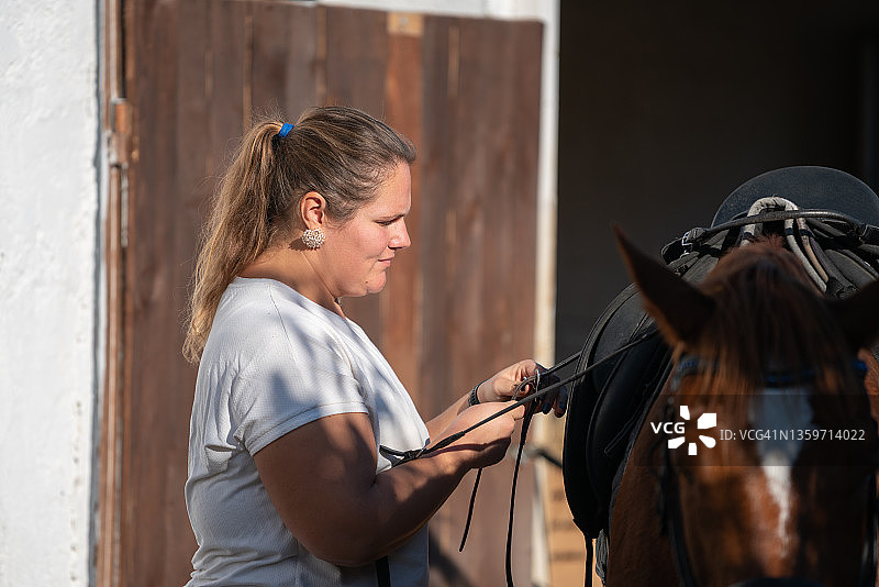 中年妇女准备马鞍，准备骑马图片素材