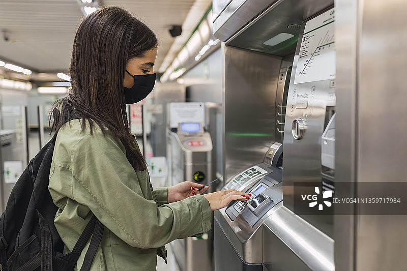 年轻女子戴口罩使用售票机图片素材