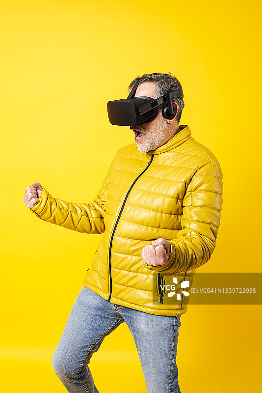 男人戴着VR模拟器在黄色背景前呼喊图片素材