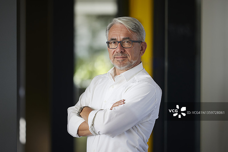 自信的商人双臂交叉站在办公室图片素材