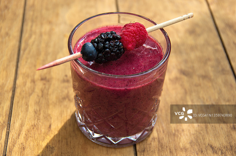 户外咖啡桌上的切割玻璃杯混合莓果冰沙图片素材