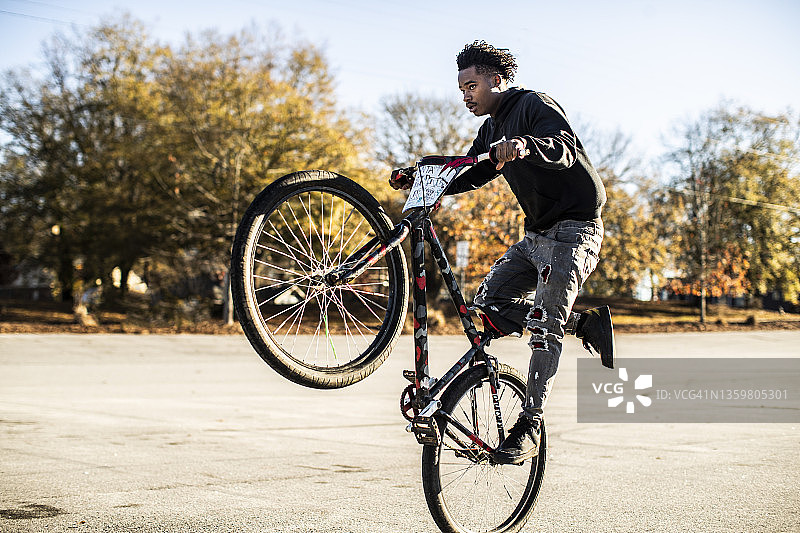 在城市地区表演前轮离地的年轻男性BMX骑手图片素材