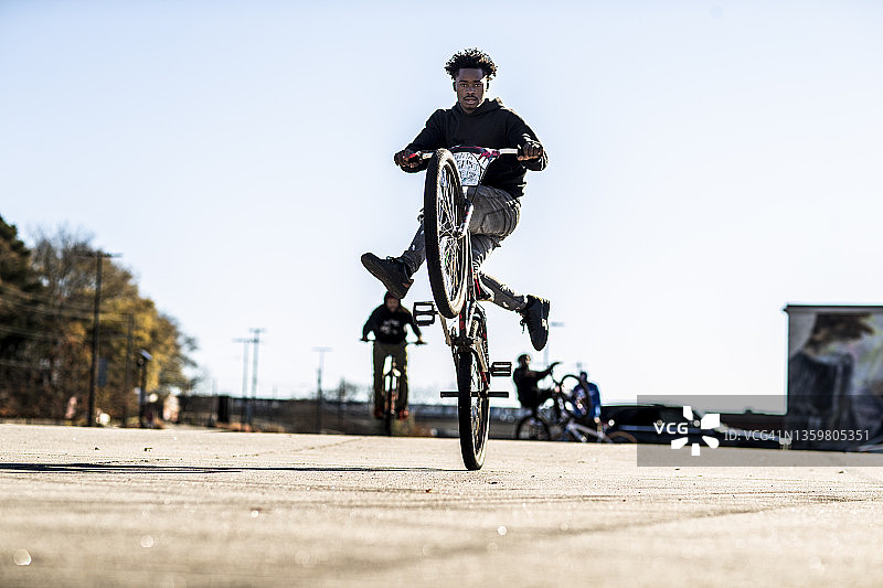 在城市地区表演前轮离地的年轻男性BMX骑手图片素材
