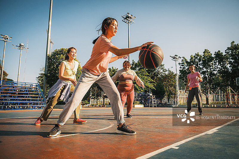 一小群亚洲年轻女性朋友喜欢在户外球场打篮球图片素材