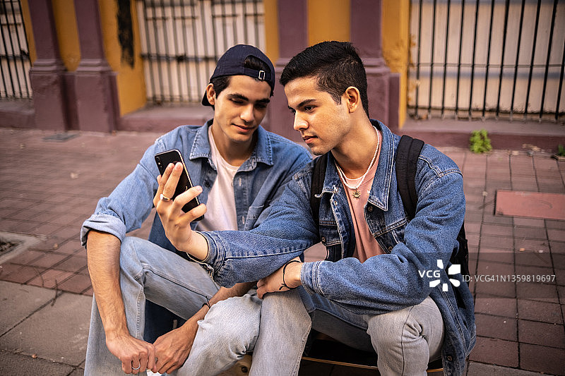 青少年男孩在户外用手机观看视频或拍照图片素材