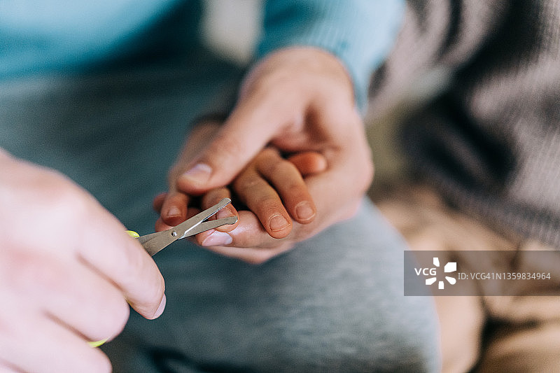 父亲给小儿子剪指甲图片素材