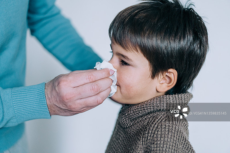 父亲在家用纸巾给儿子擦鼻涕图片素材