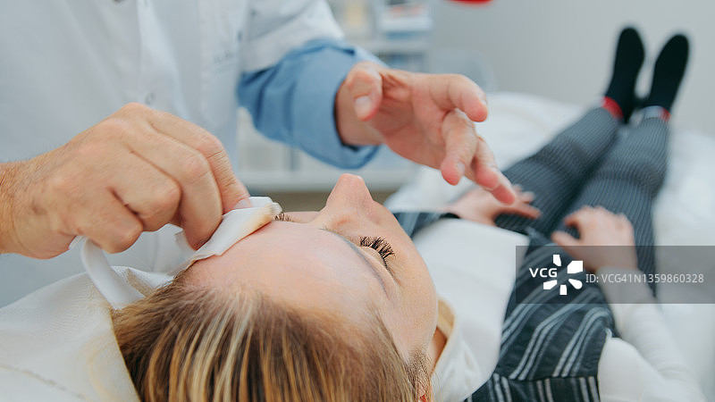 整形外科医生在美容操作前用抗菌餐巾清洁女顾客额头图片素材