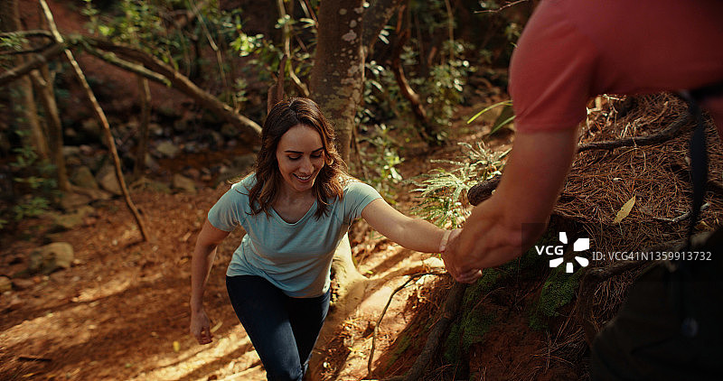 男人帮助伴侣在森林中探索的场景图片素材