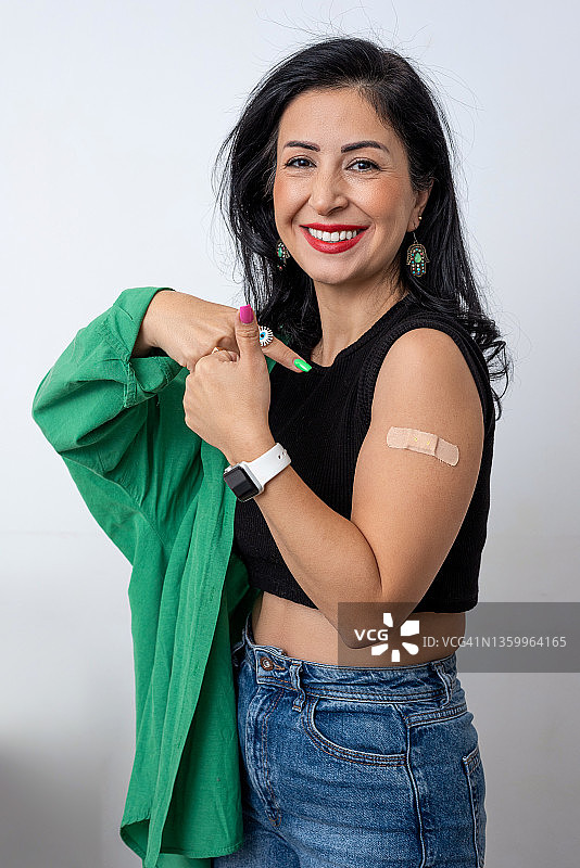 接种疫苗的喜悦，妇女展示手臂上的创可贴图片素材