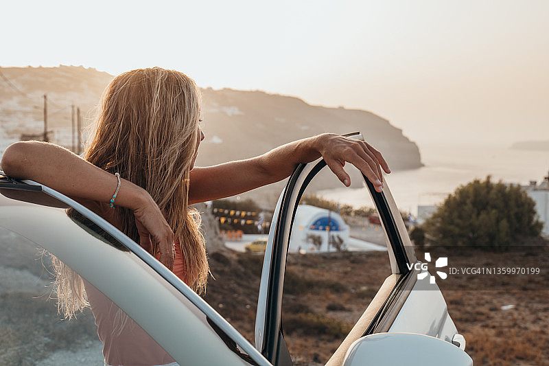 年轻女子开敞篷车欣赏海岸线，公路旅行概念图片素材