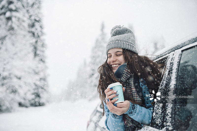 在下雪天喝热饮的微笑女人图片素材