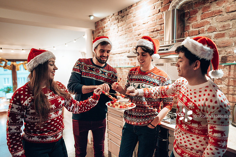 朋友们穿着圣诞毛衣在家一起吃饭图片素材